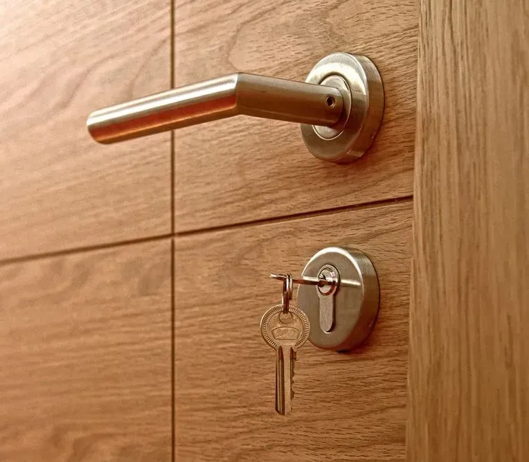 Door Handle and Key in the Lock on a Wooden Door — Shaine Hunter Locksmiths in Mount Isa City, QLD