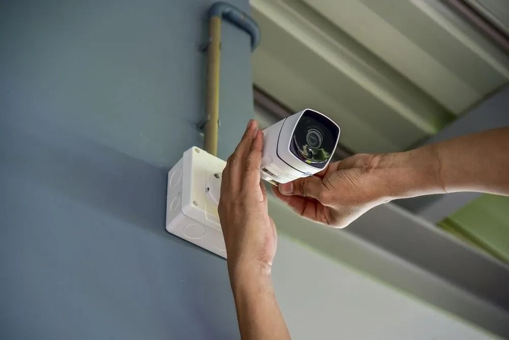 Hands Installing a White Security Camera — Shaine Hunter Locksmiths in Mount Isa City, QLD