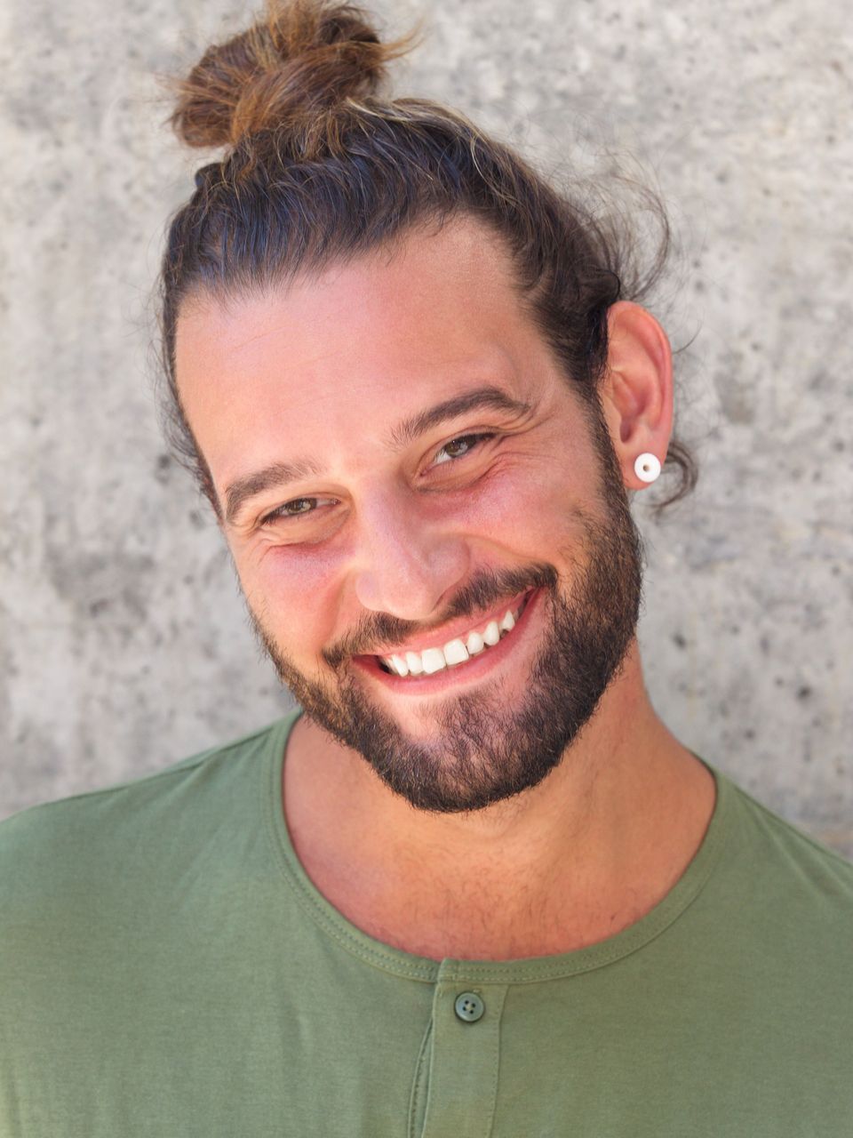 A man with a beard and a bun is smiling for the camera.