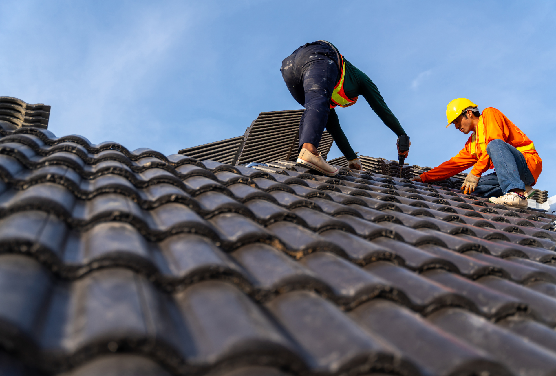 Two men are working on the roof of a house.