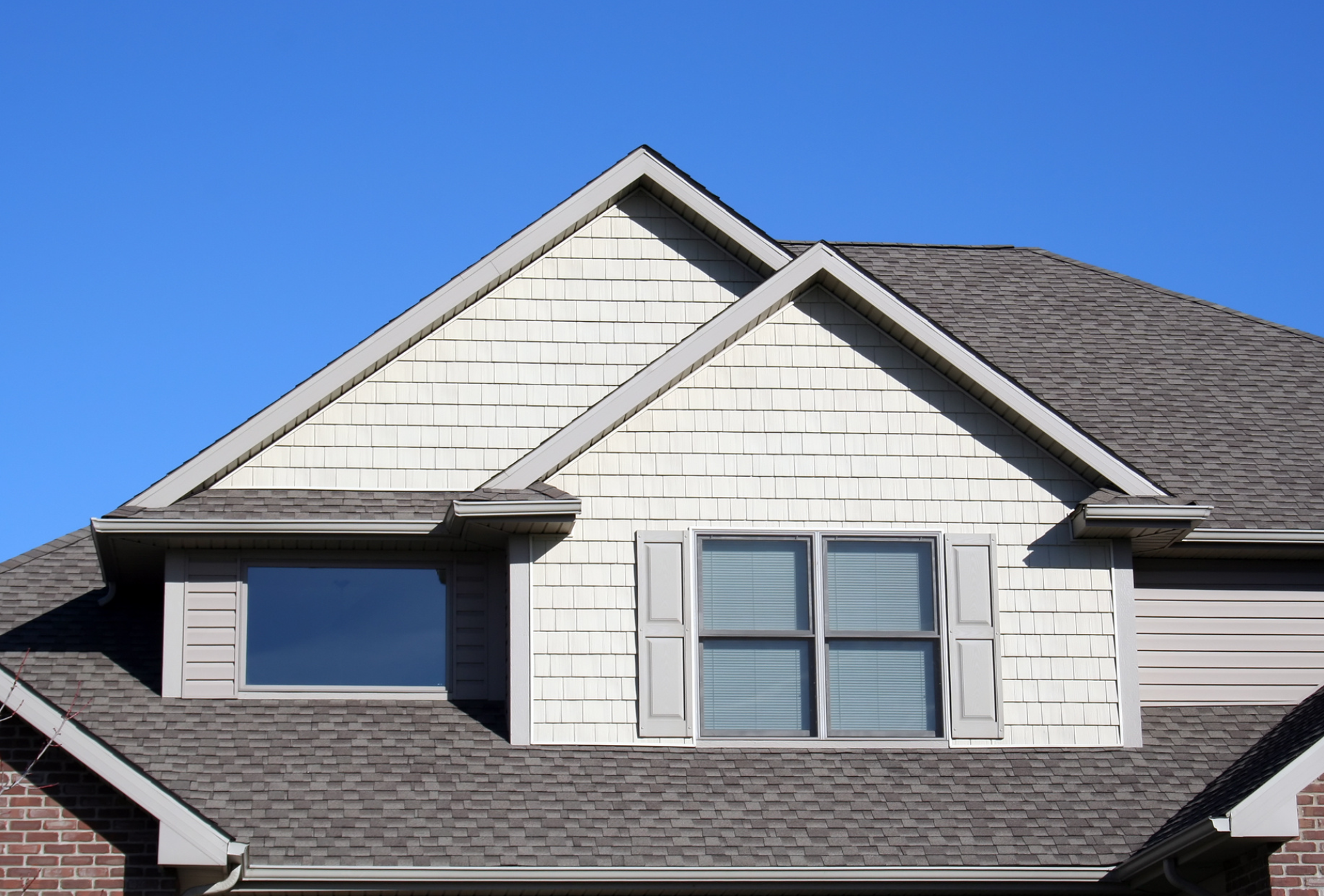 The roof of a house with a window and shutters on it.