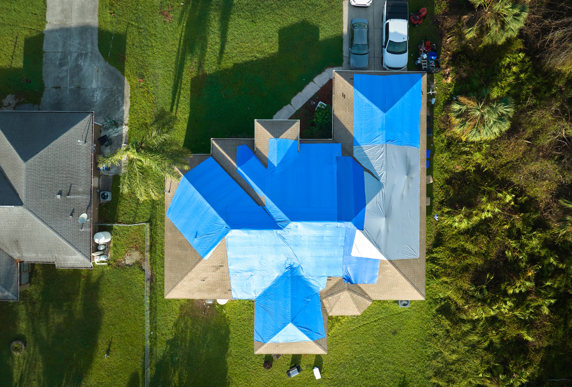 An aerial view of a house with a blue tarp on the roof.