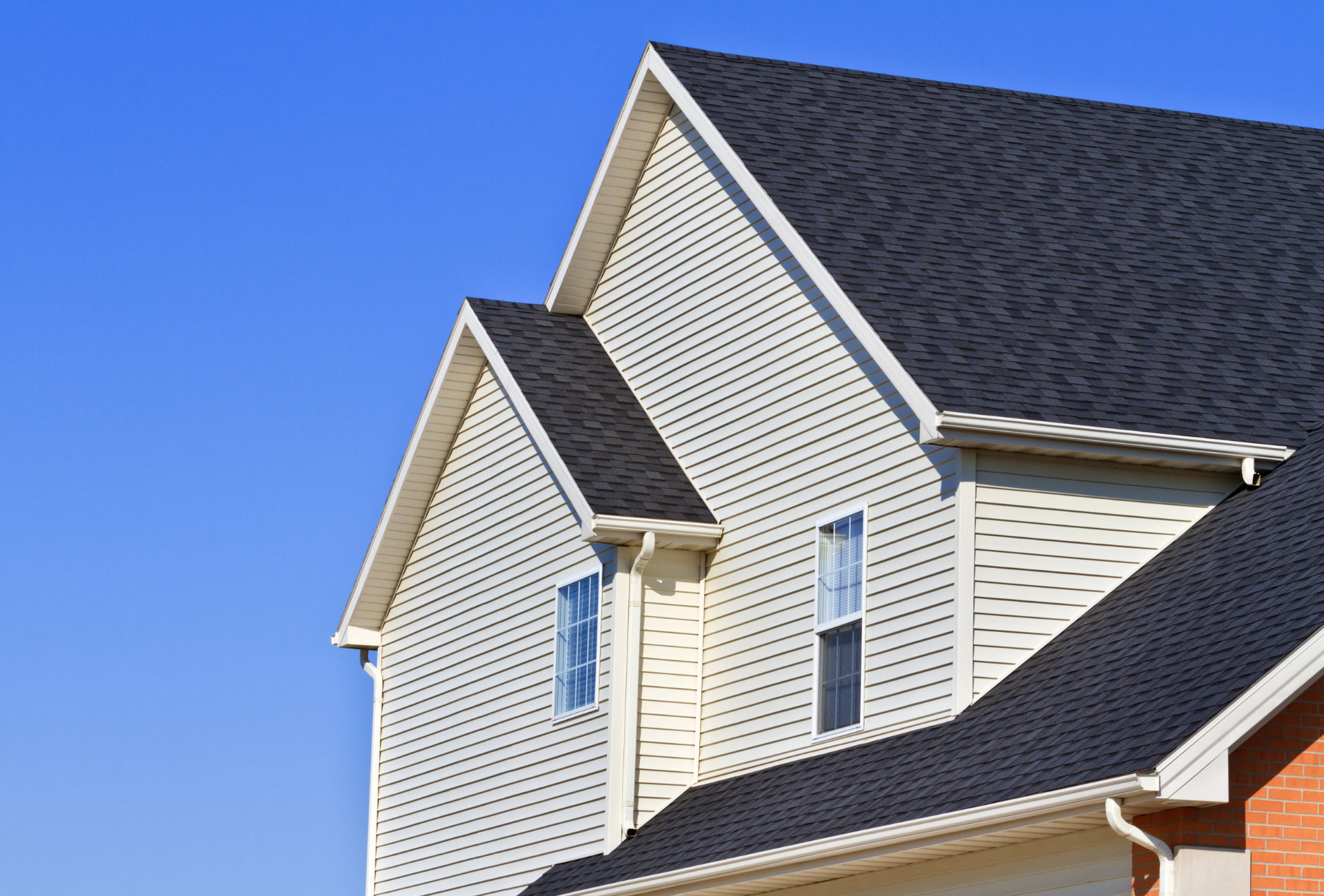 A white house with a black roof and a blue sky in the background.