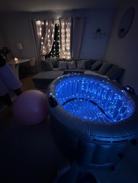 A living room with a birthing pool filled with blue lights.