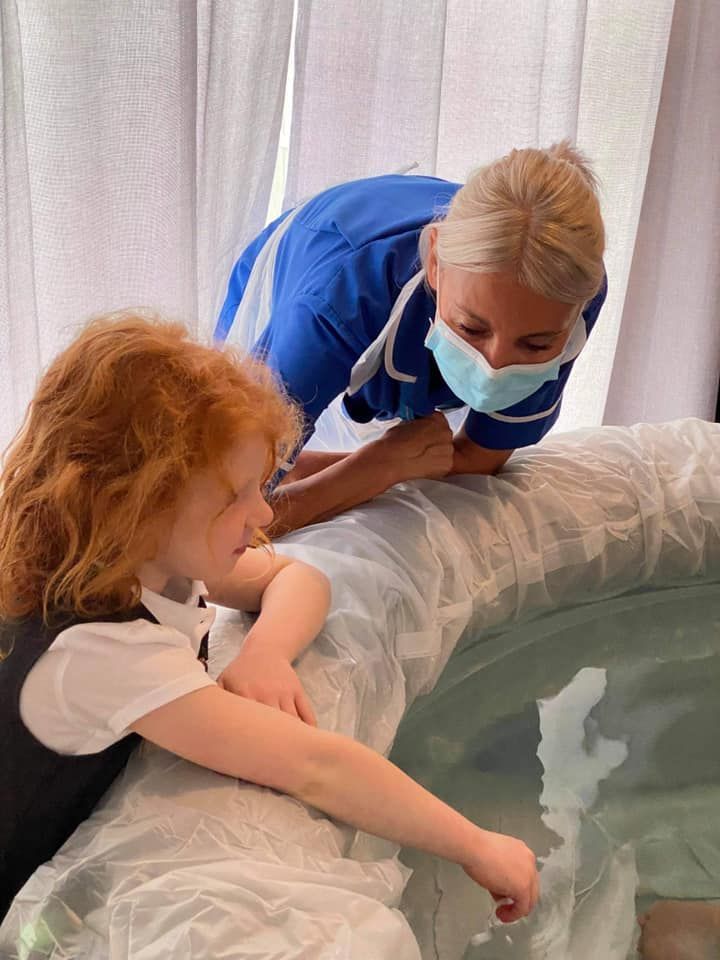 A midwife and a young girl watch as a other gives birth in water