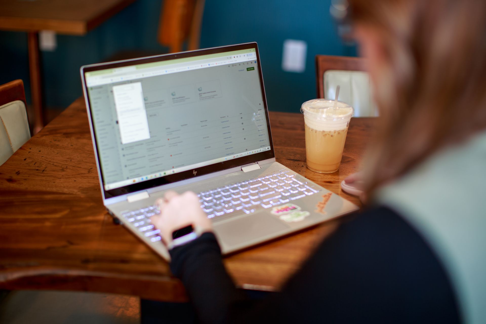 Person using a laptop at a table, coffee nearby.