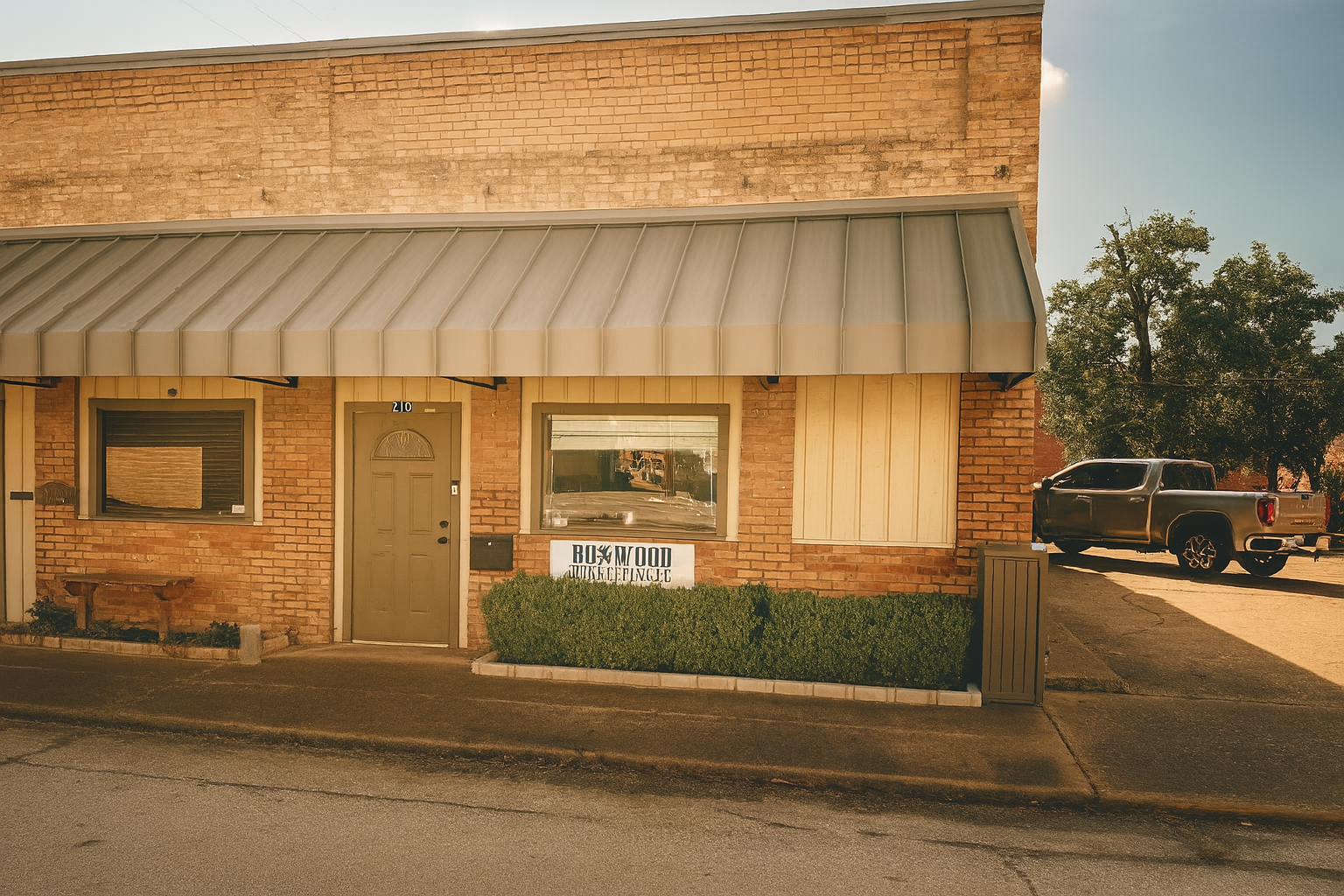 Brick building with a shopfront awning, door, and windows. A truck is parked to the right.