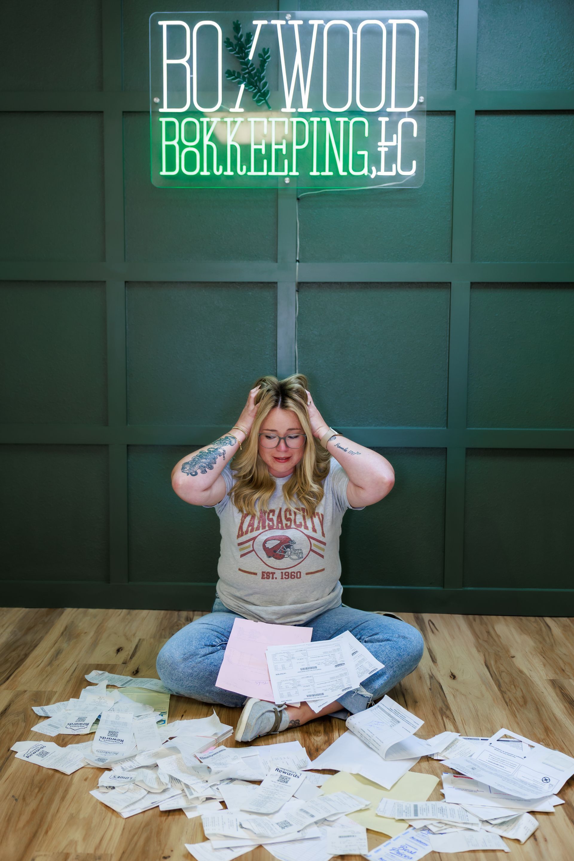 Woman overwhelmed by paperwork, sitting on floor in front of a 