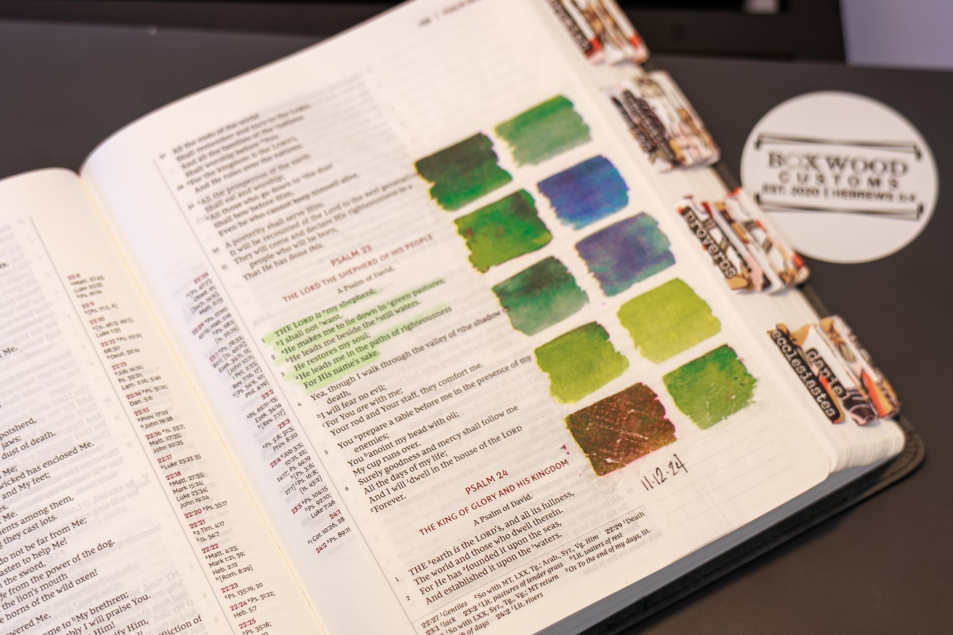 Open Bible with color swatches and tabs, featuring watercolor art for journaling, next to a 