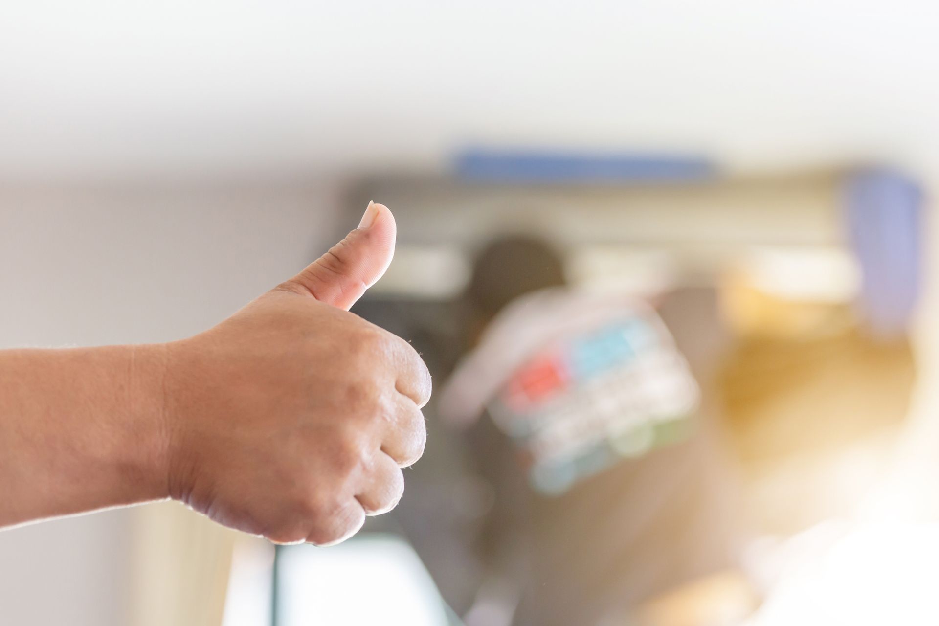 Repairman giving thumbs-up while performing air conditioning installation successfully.