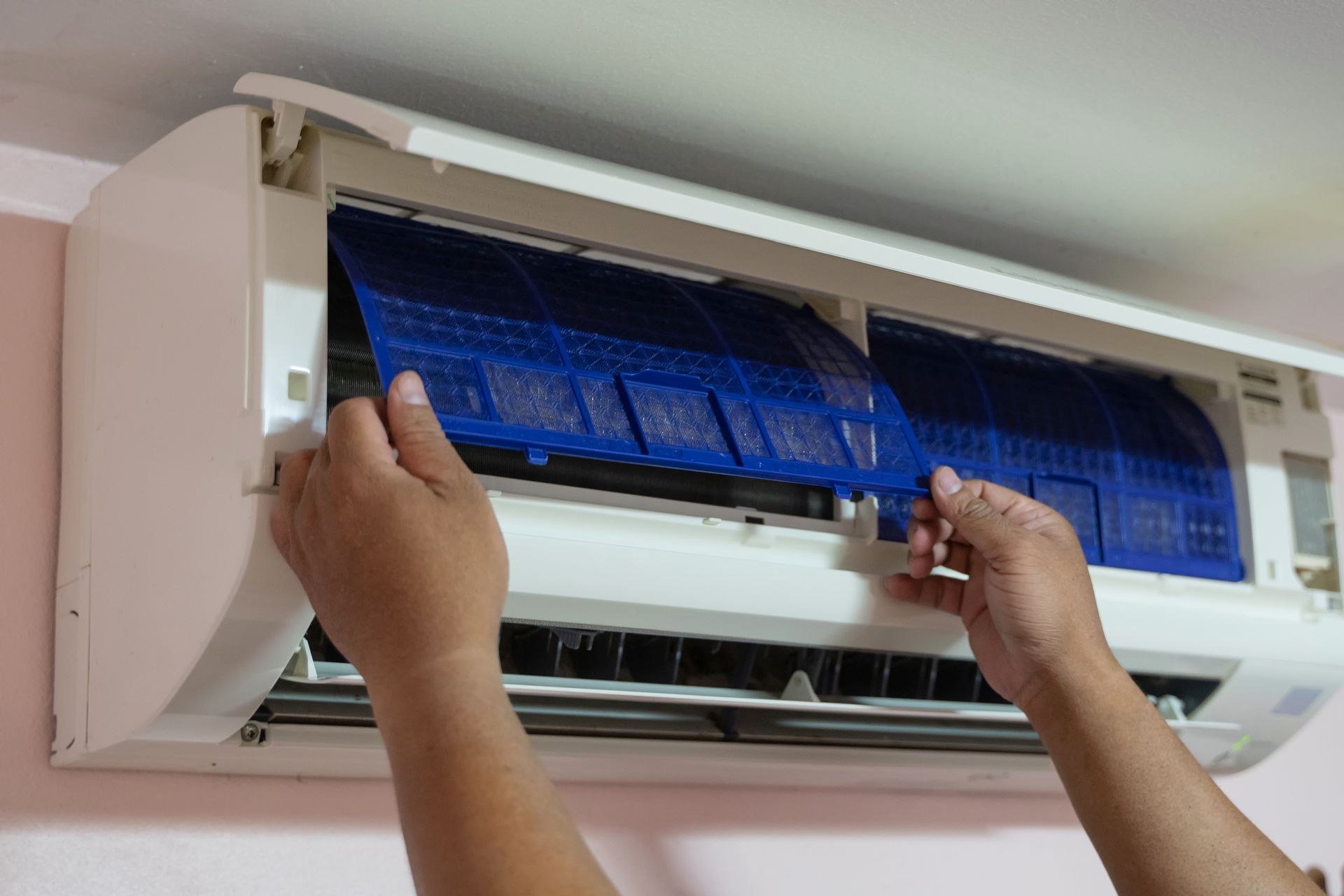 Male technician handling blue AC filters, representing air conditioning installations.