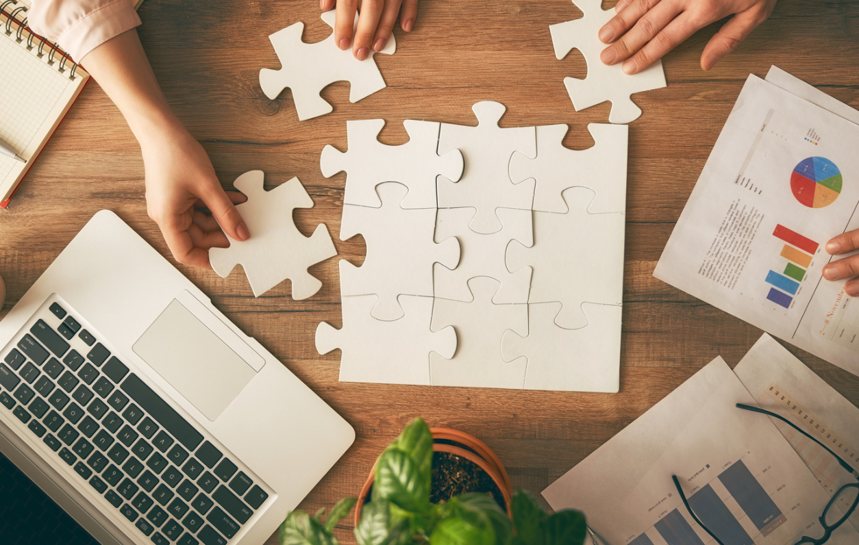 people putting a puzzle together on a desk