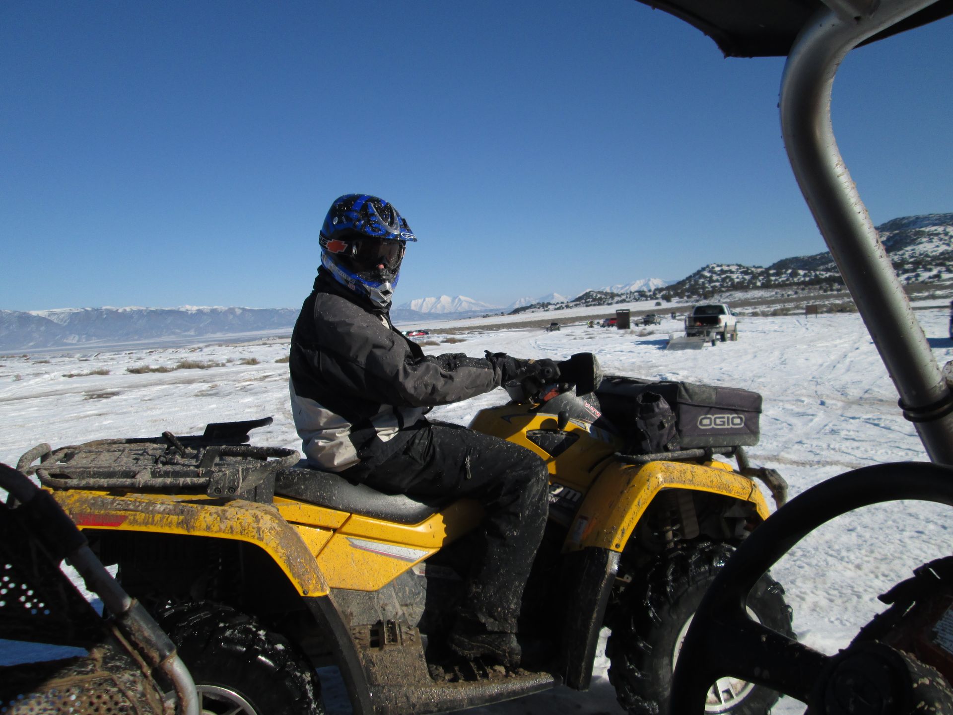 A man is riding a yellow atv in the snow