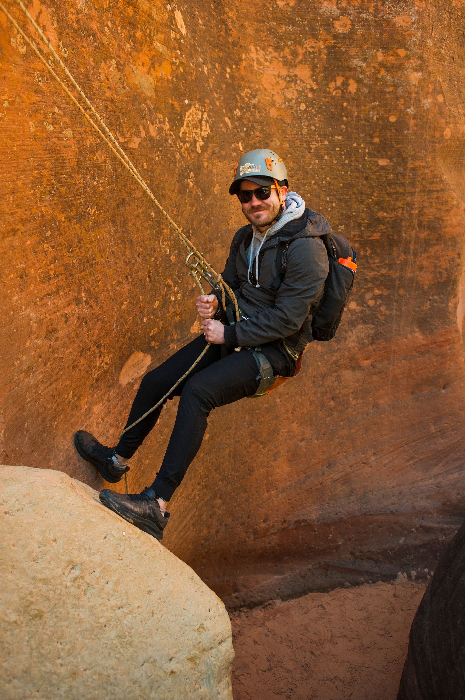 A man is sitting on a rock holding a rope.