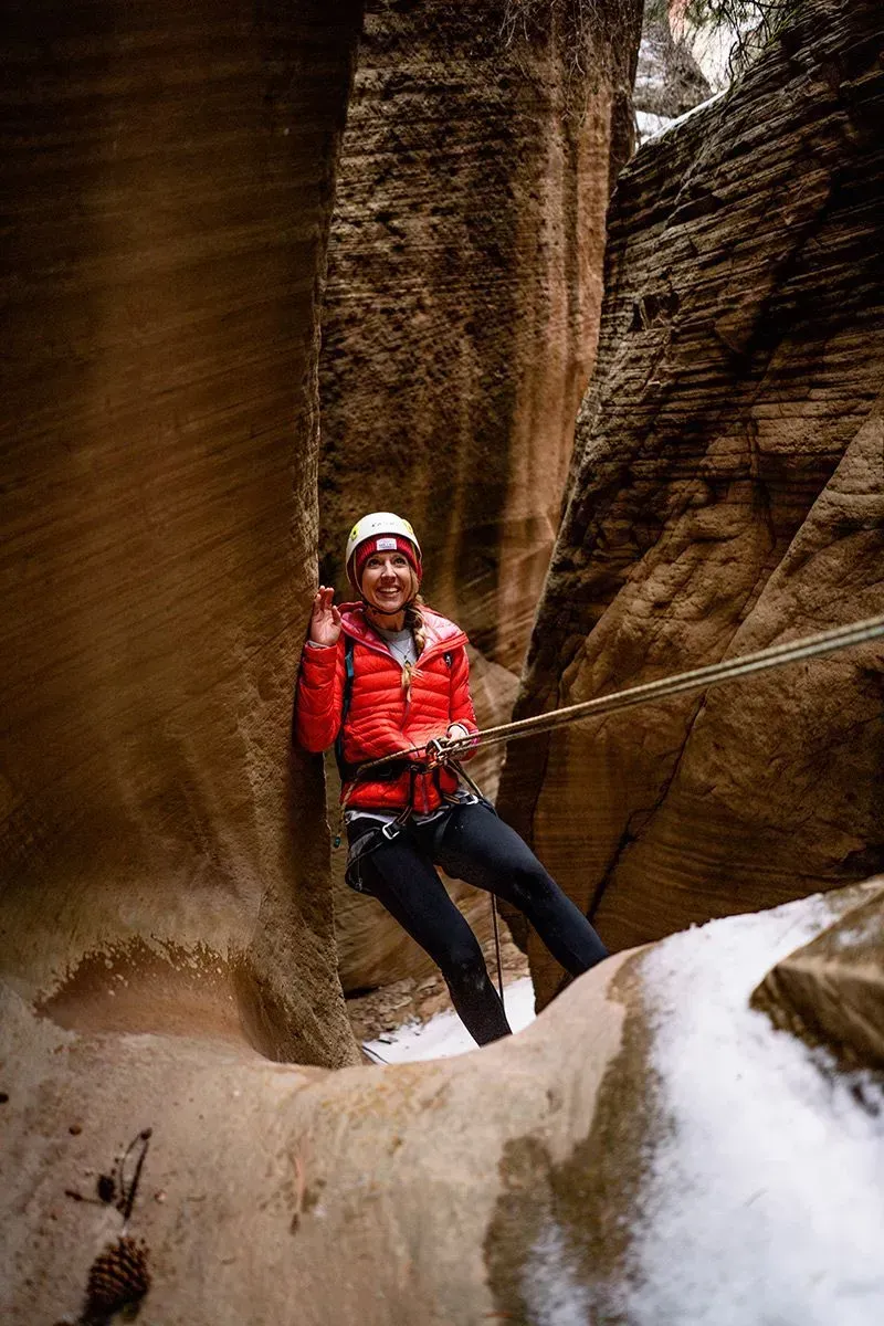 A woman is canyoneering through the canyon