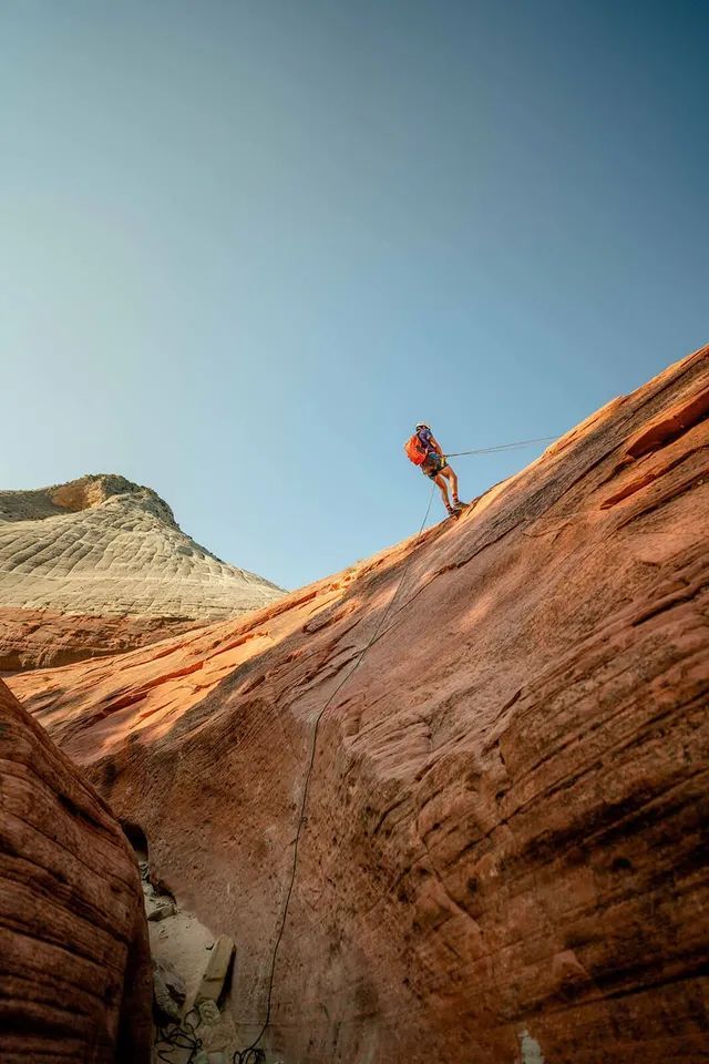 A man is climbing up a rock wall in the desert.