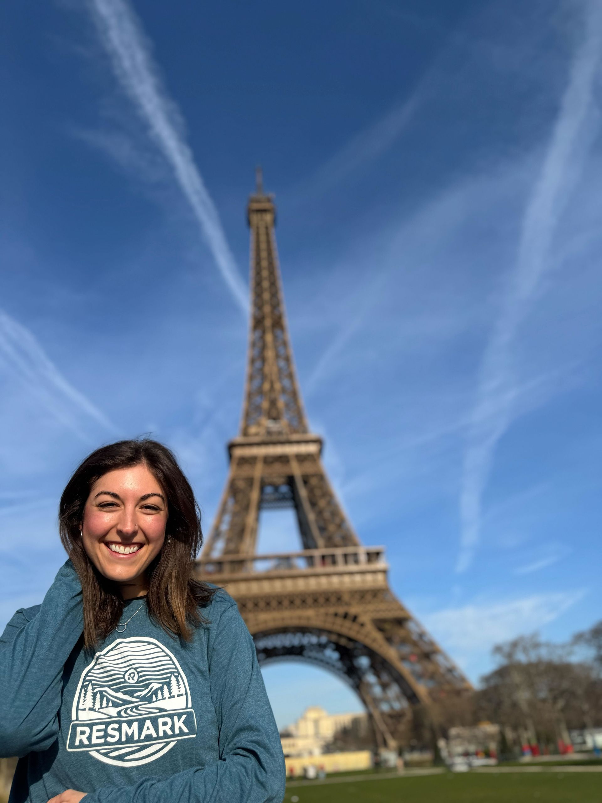 A woman is standing in front of the eiffel tower in paris.