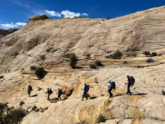 A group of people are hiking up a rocky hillside.
