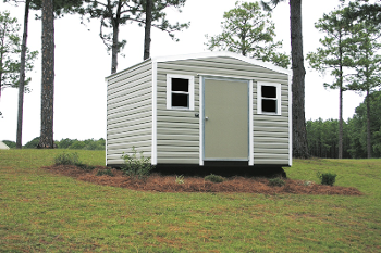 A small shed with the door open is sitting on top of a lush green field.