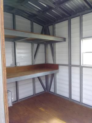 The inside of a shed with shelves and a window.