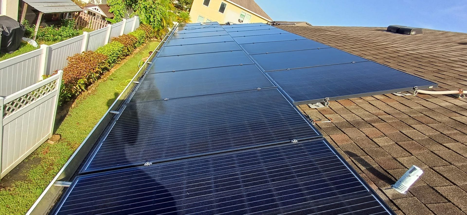 There are many solar panels on the roof of a house.