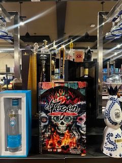 Menu in front of a liquor display featuring Day of the Dead theme. Blue and white bottles on either side.