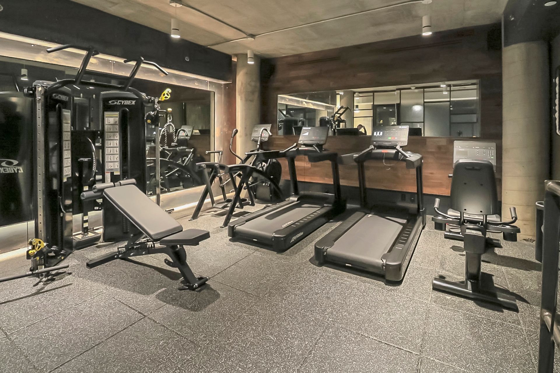 Gym with exercise equipment, including treadmills, weight bench, and weight machines.