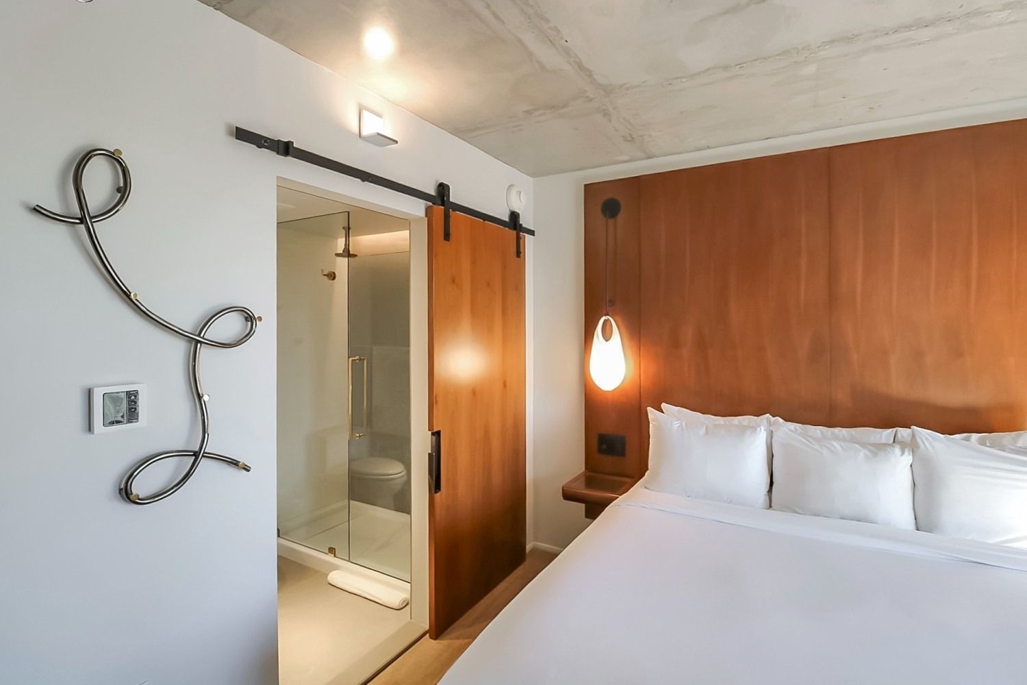 Hotel room with bed, sliding barn door to shower, and decorative wall art.