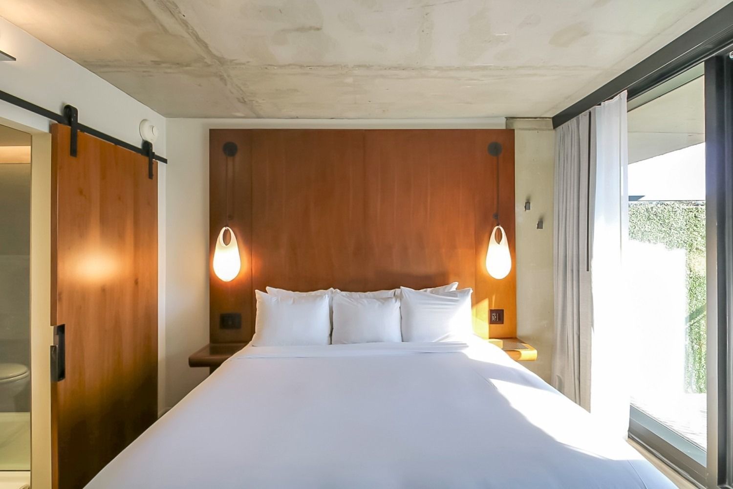 Bedroom with a large bed, wooden headboard, and sliding barn door to the left.