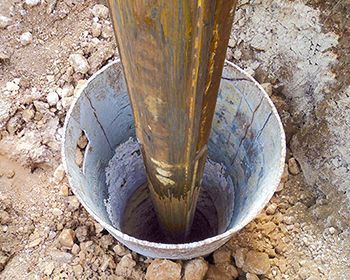 A metal pole is being drilled into a hole in the ground.