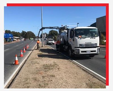 A vacuum truck is driving down the side of a road.