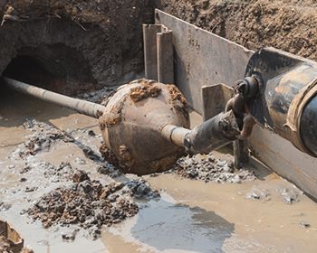 A pipe is stuck in the mud in a trench.