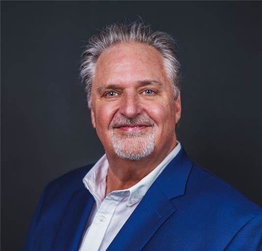 A man is holding a dog in his arms and the dog is wearing a sweater.