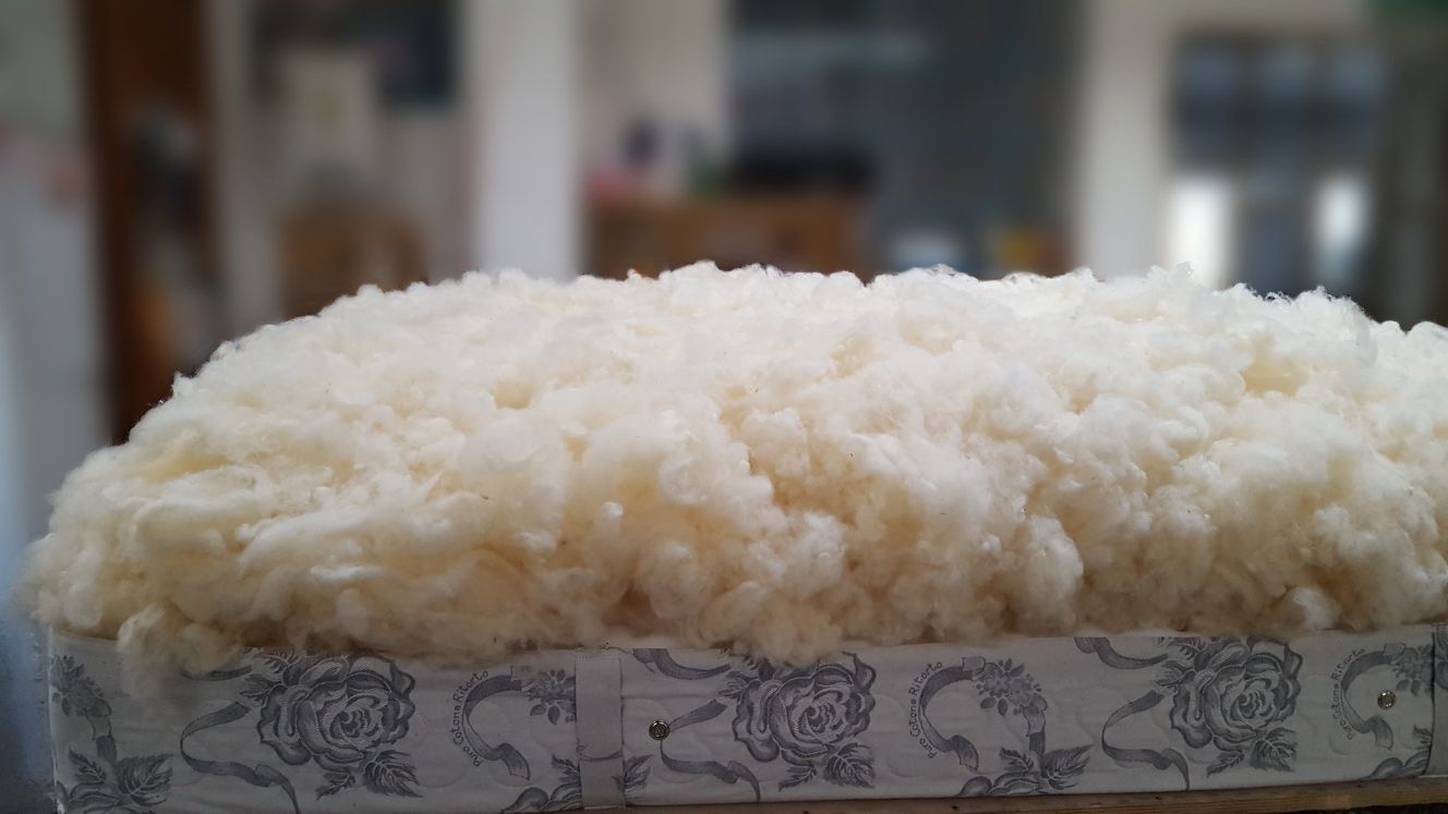 Imbottitura in fibra soffice color crema sopra una scatola con motivo floreale, probabilmente parte di un rivestimento.