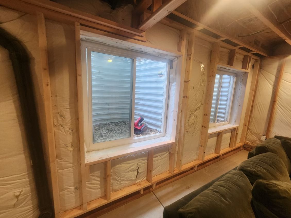 Basement with two windows. Framing, insulation, and a section of couch visible.