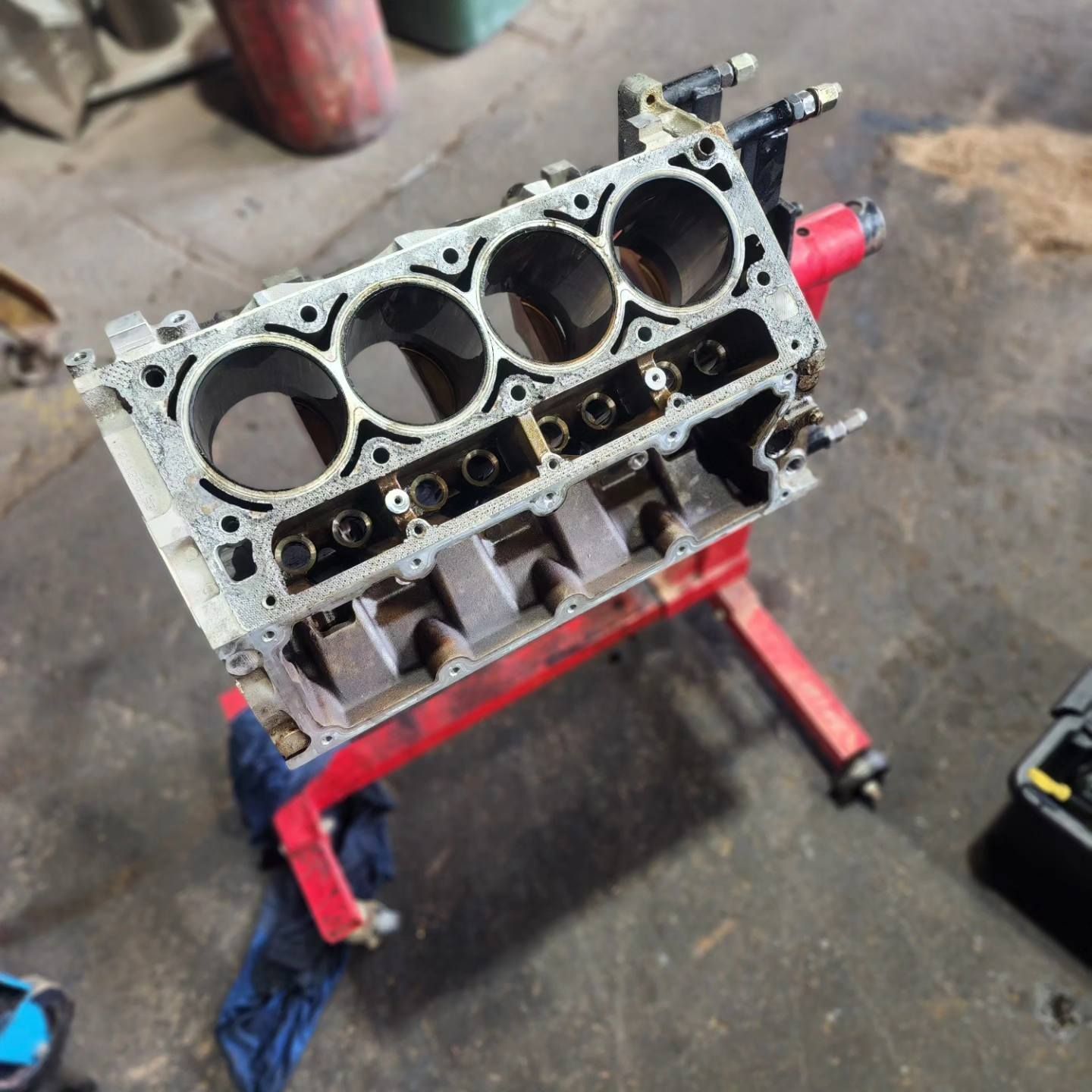 A Cylinder Block is Sitting on a Red Stand in a Garage — Currie Bros Engine Reconditioners in Forster, NSW