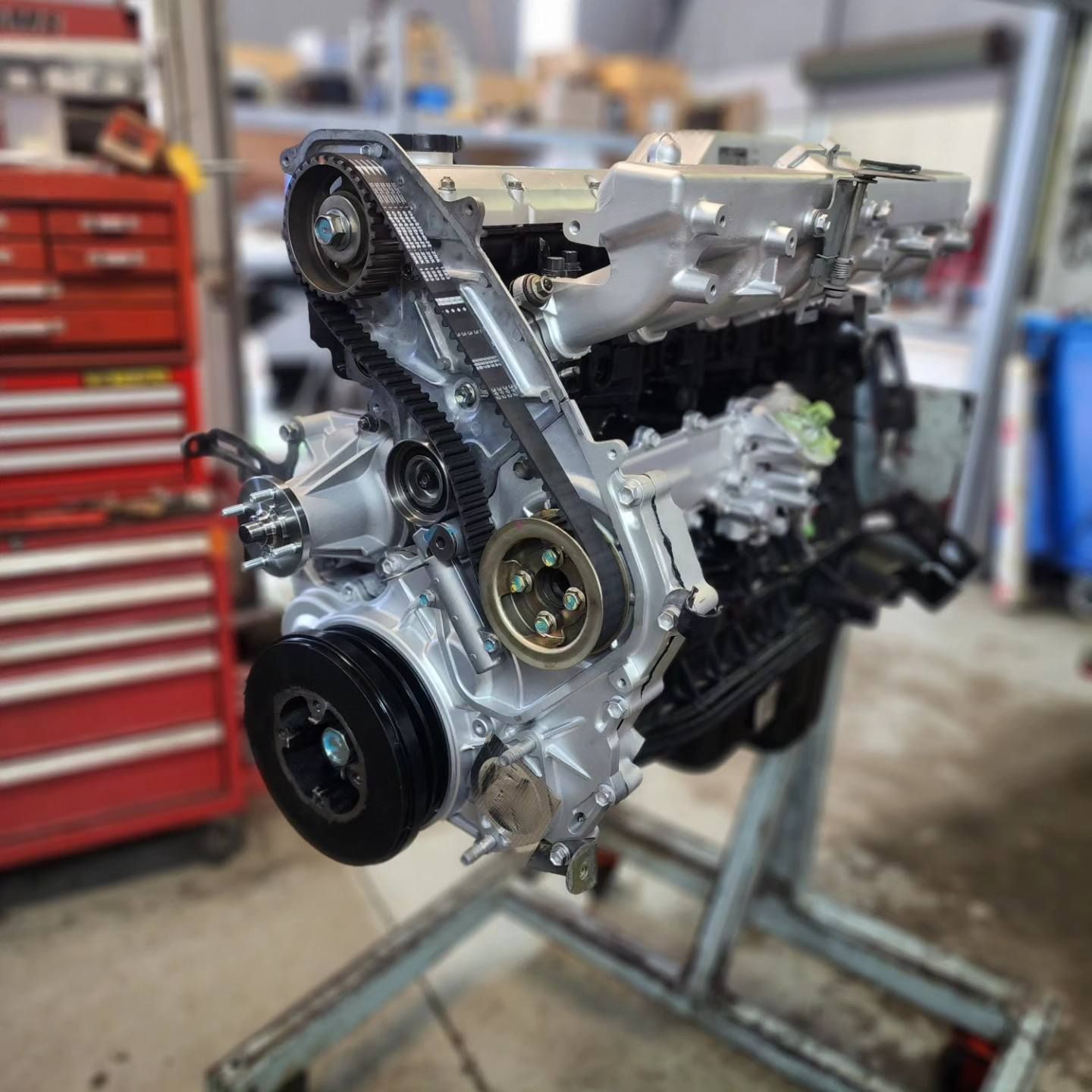 A Car Engine is Sitting on a Stand in a Garage — Currie Bros Engine Reconditioners in Hallidays Point, NSW