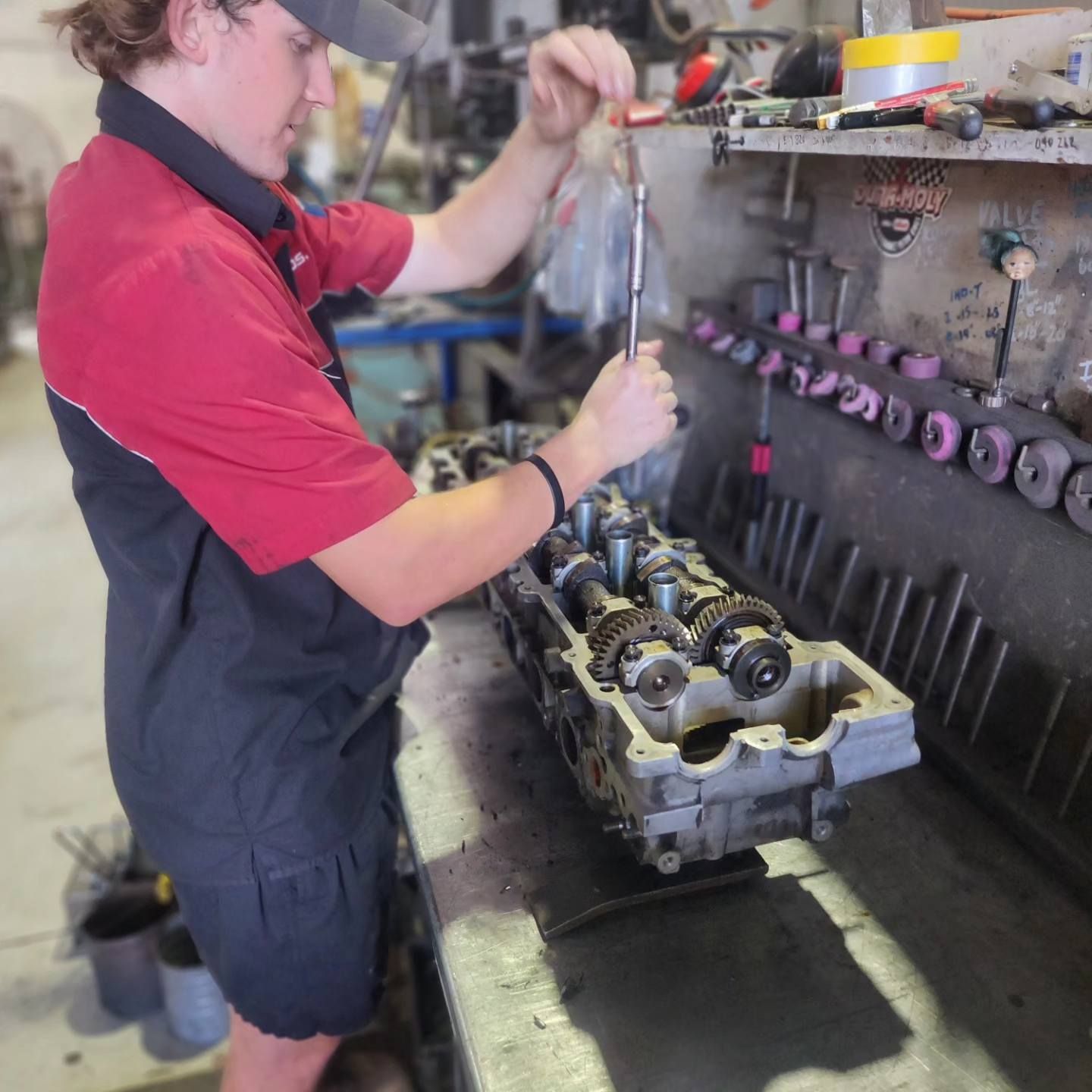 A Man in a Red Shirt is Working on a Machine — Currie Bros Engine Reconditioners in Taree, NSW