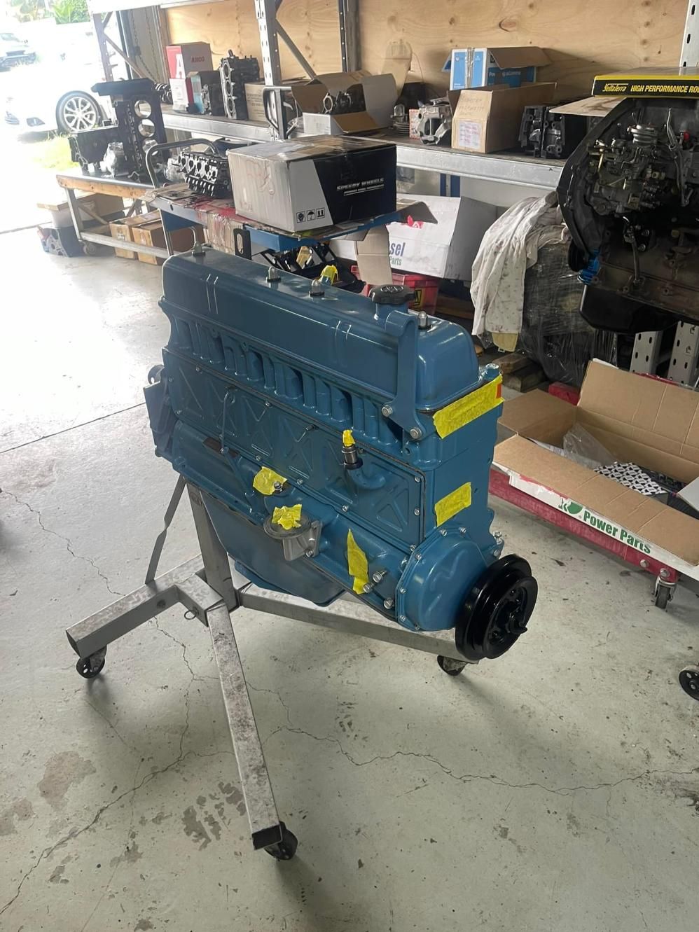 A Blue Engine is Sitting on a Stand in a Garage — Currie Bros Engine Reconditioners in Taree, NSW