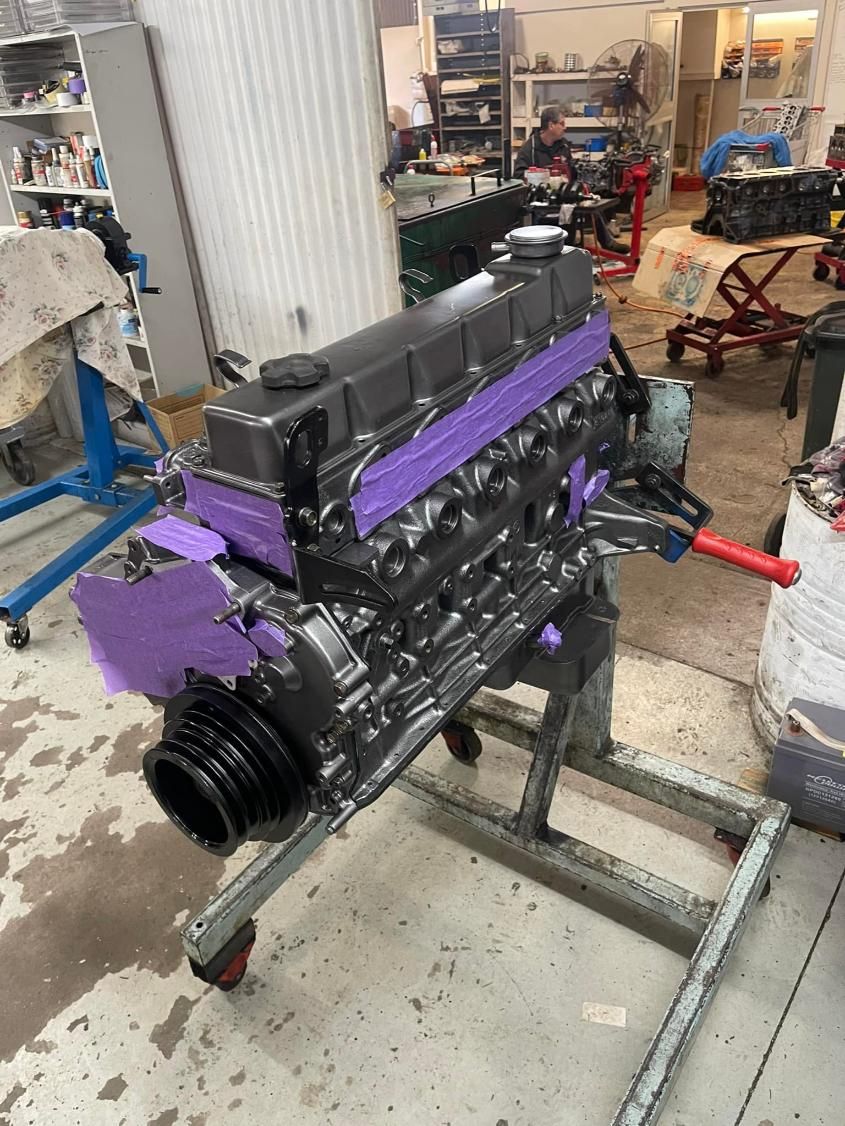 A Black and Purple Engine is Sitting on a Stand in a Garage — Currie Bros Engine Reconditioners in Gloucester, NSW