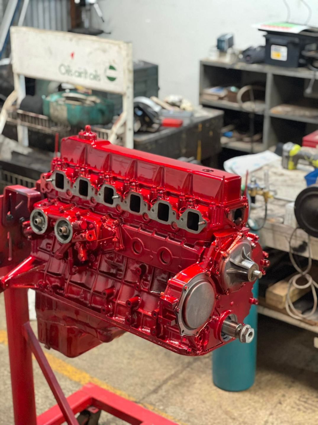 A Red Engine is Sitting on a Red Stand in a Garage — Currie Bros Engine Reconditioners in Coffs Harbour, NSW