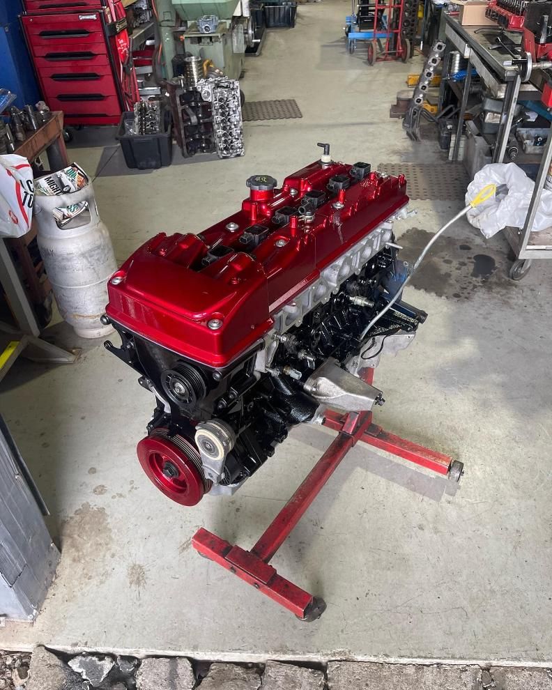 A Red Engine is Sitting on a Red Stand in a Garage — Currie Bros Engine Reconditioners in Taree, NSW
