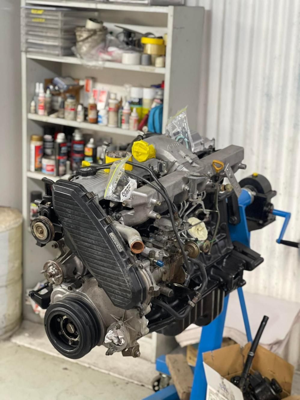 A Car Engine is Sitting on Top of a Blue Stand in a Garage — Currie Bros Engine Reconditioners in Taree, NSW