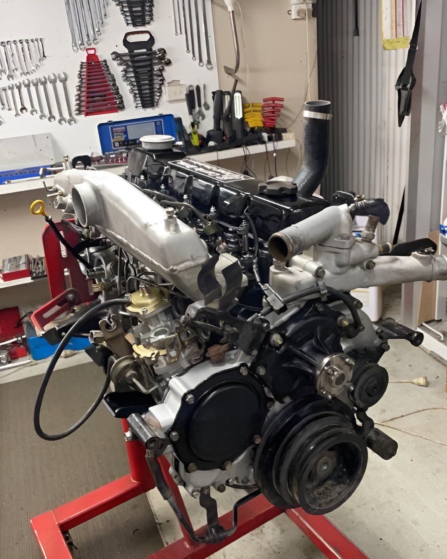 A Car Engine is Sitting on a Red Stand in a Garage — Currie Bros Engine Reconditioners in Kempsey, NSW