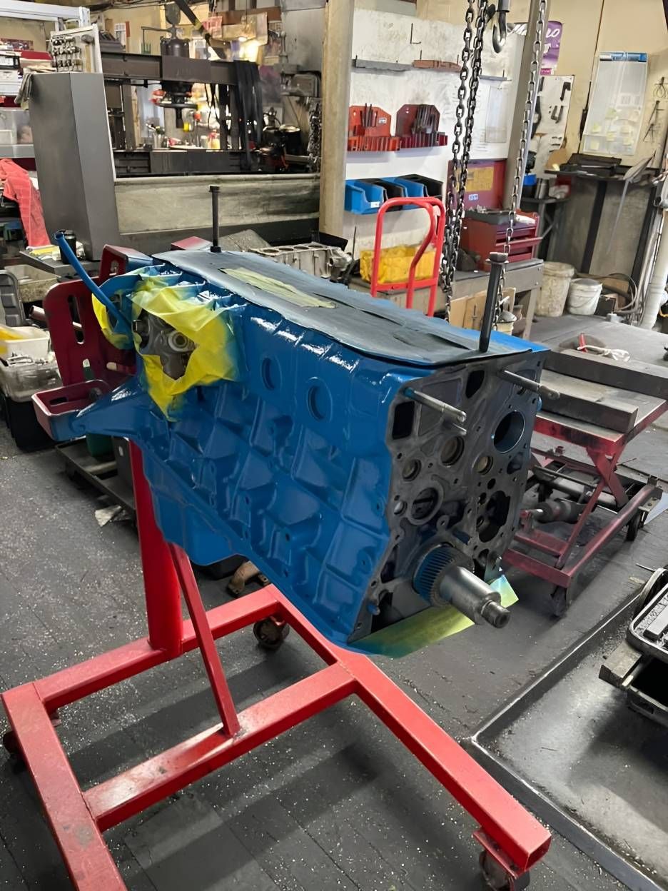 A Blue Engine Block is Sitting on a Red Stand in a Garage — Currie Bros Engine Reconditioners in Coffs Harbour, NSW