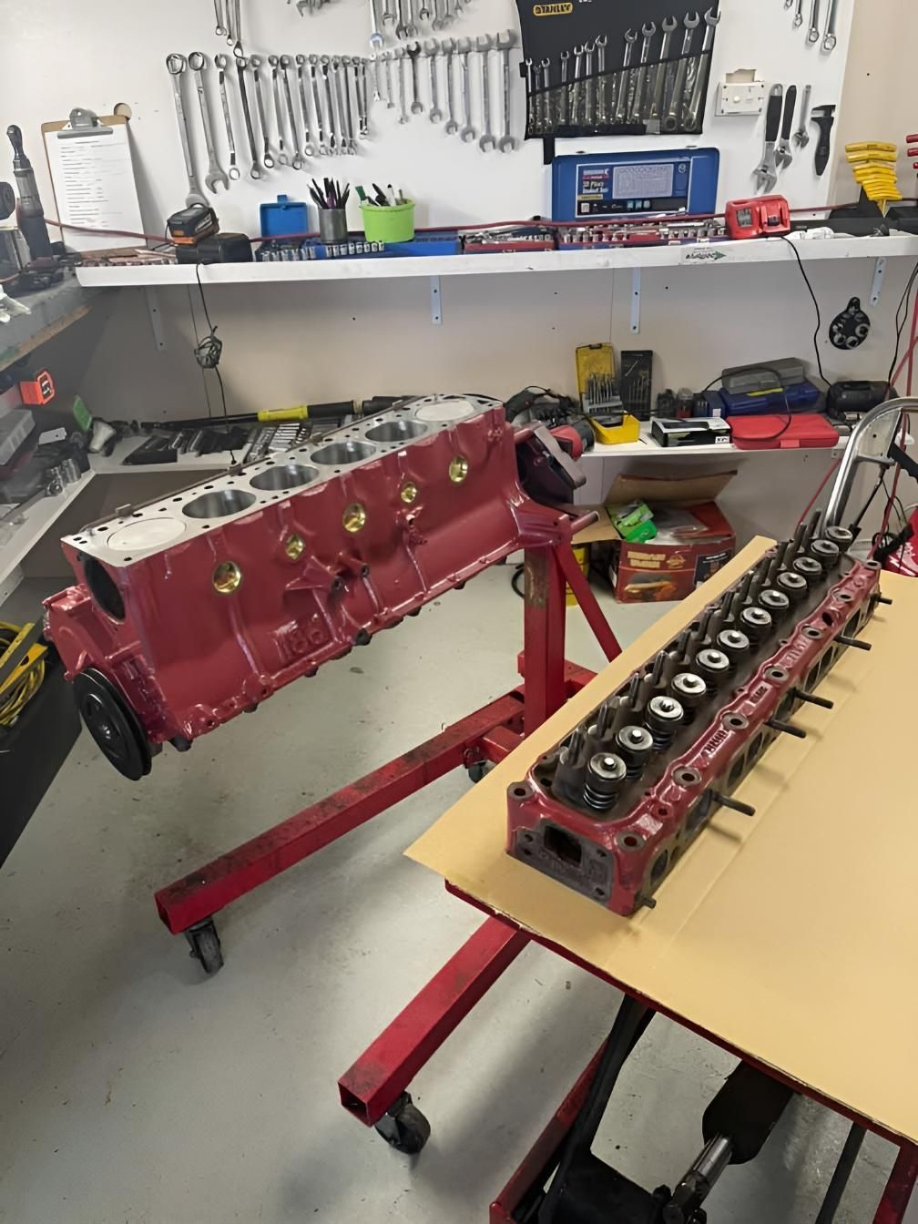 A Red Engine is Sitting on Top of a Wooden Table in a Garage — Currie Bros Engine Reconditioners in Taree, NSW