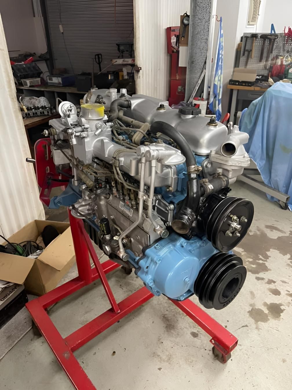 A Blue Engine is Sitting on a Red Stand in a Garage — Currie Bros Engine Reconditioners in Hallidays Point, NSW