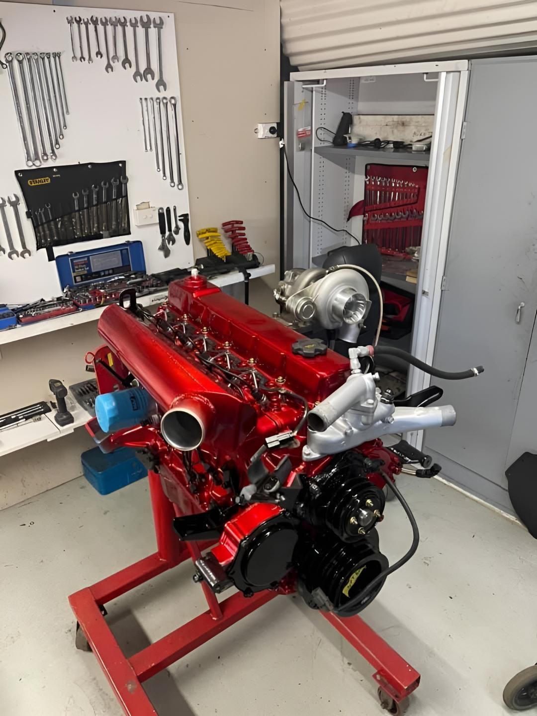 A Red Engine is Sitting on a Red Stand in a Garage — Currie Bros Engine Reconditioners in Hallidays Point, NSW