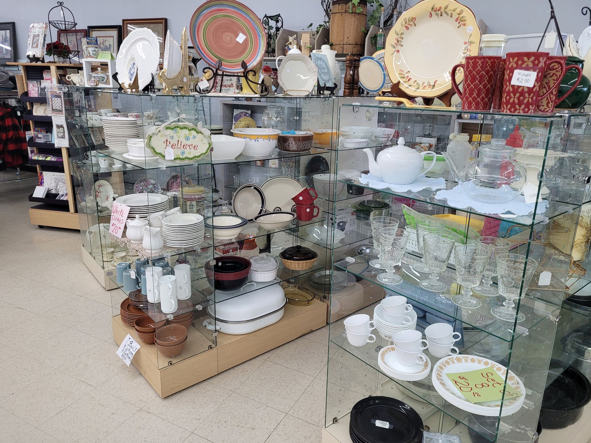 A thrift store filled with lots of plates , bowls , cups and glasses.