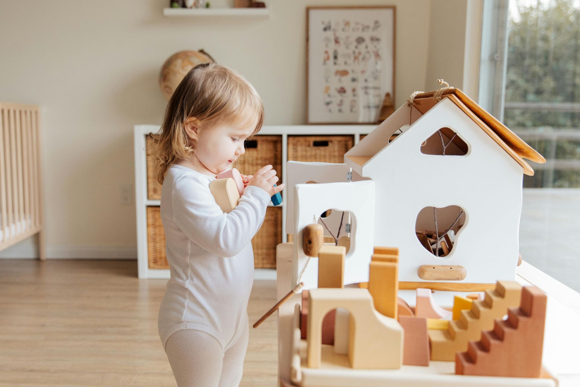 Toddler playing with wooden toy house, indoor setting.